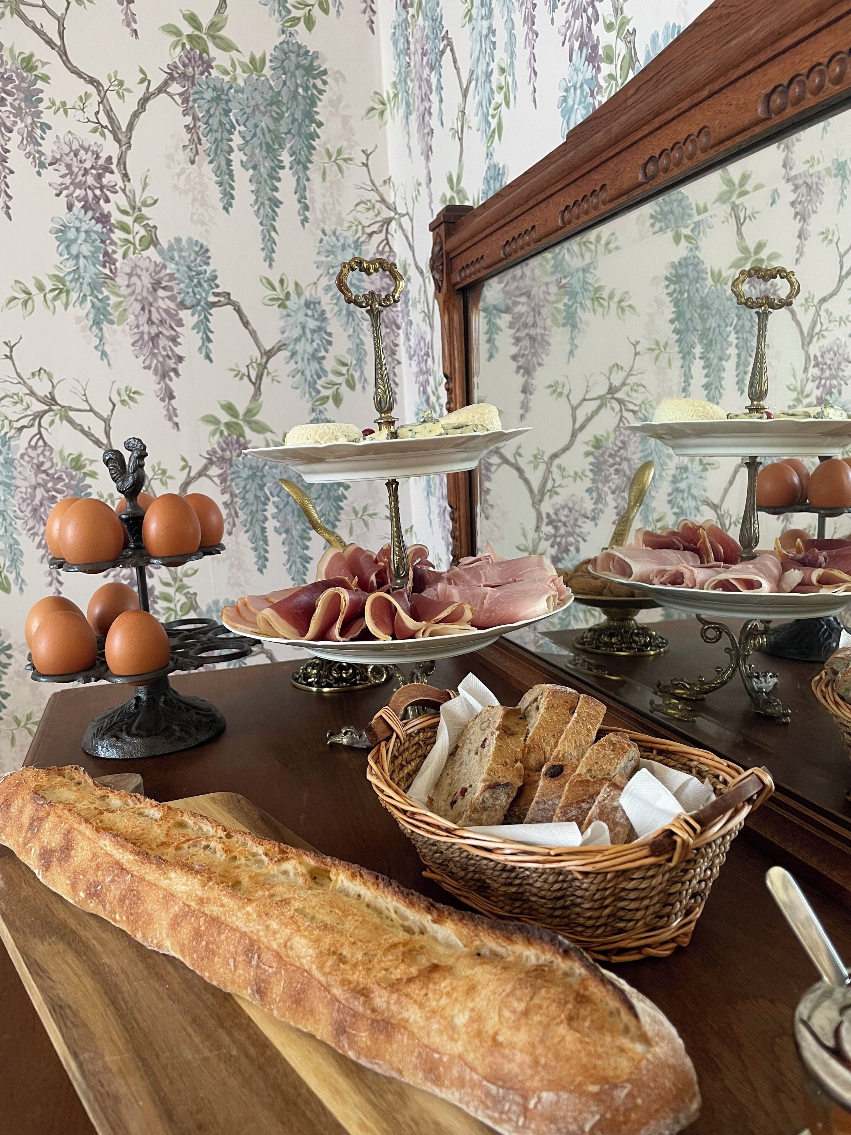A buffet table with bread, eggs, ham, and a wicker basket.