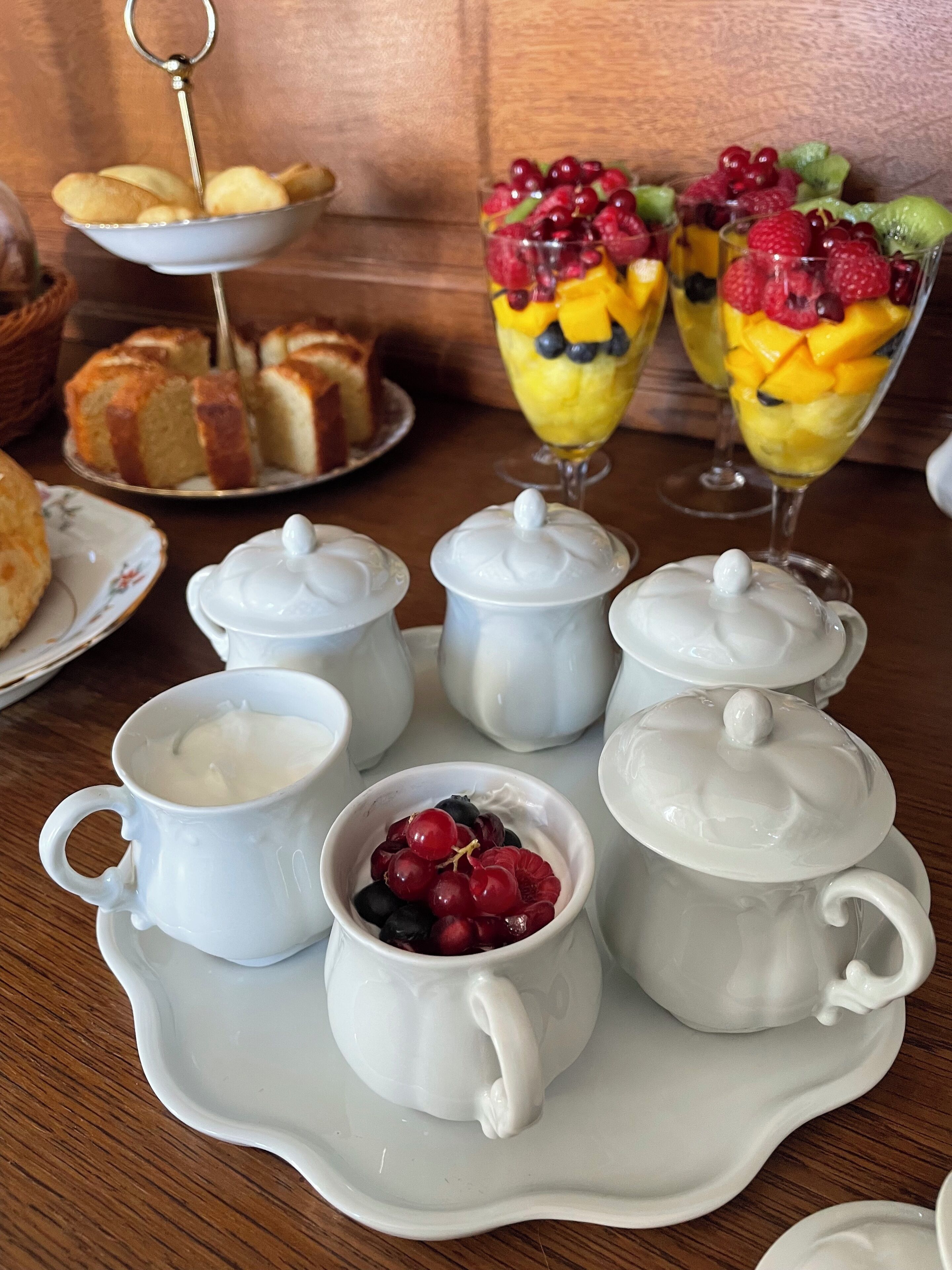 Une table avec des théières blanches, des tasses et un bol de baies.