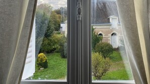 Una ventana con vistas a un jardín y un edificio.