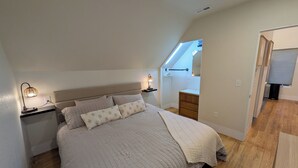Een slaapkamer met een bed, nachtkastjes, een dressoir en een dakvenster.