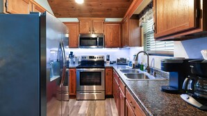 Une cuisine moderne avec des meubles en bois, des appareils en acier inoxydable, des plans de travail en granit et un plafond en bois.