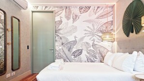 A bedroom with a large bed, a door, and a wall with a leaf pattern. - Chic & Trendy Studio in Historic Center (Lisboa)