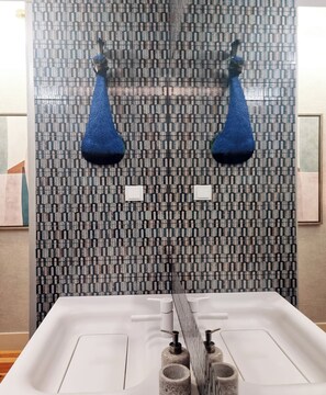 A bathroom with a patterned tile backsplash, a white sink with two soap dispensers, and a mirror above the sink.