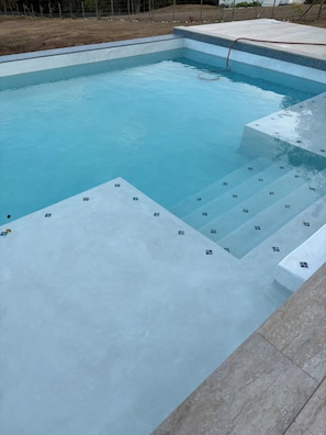 A rectangular swimming pool with clear blue water, a tiled edge, and steps leading into the water. - Luxury 2 BR Island Getaway Featuring Spectacular Views w/King Beds (Vieques)