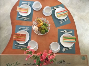 A round table with a central fruit basket, surrounded by plates with striped napkins, and empty bowls and cutlery. - Luxury 2 BR Island Getaway Featuring Spectacular Views w/King Beds (Vieques)