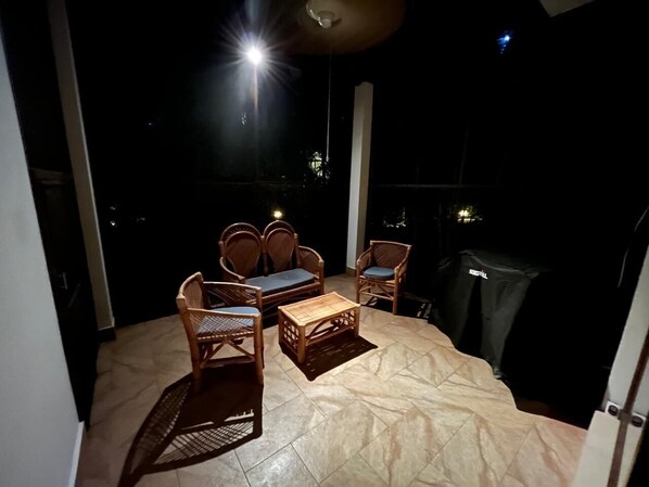 A balcony with wicker furniture, a table, and a grill. - Bright 2-bedroom 2 bath apartment with AC in peaceful Akumal and nearby Tulum (Akumal)