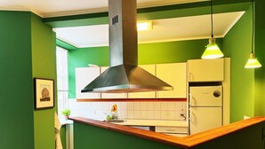 A kitchen with green walls, a wooden countertop, a stainless steel range hood, a white refrigerator, and pendant lights. - Greenbrook Homes (Aalborg)