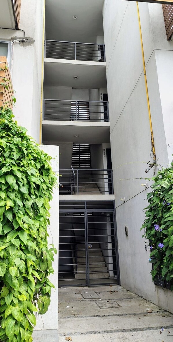 A multi-level building with a central staircase, metal railings, and a concrete exterior. - 2 bedroom apartment, ground floor with patio, 20 min airport and 8 min Tlaquepaque (Tlaquepaque)