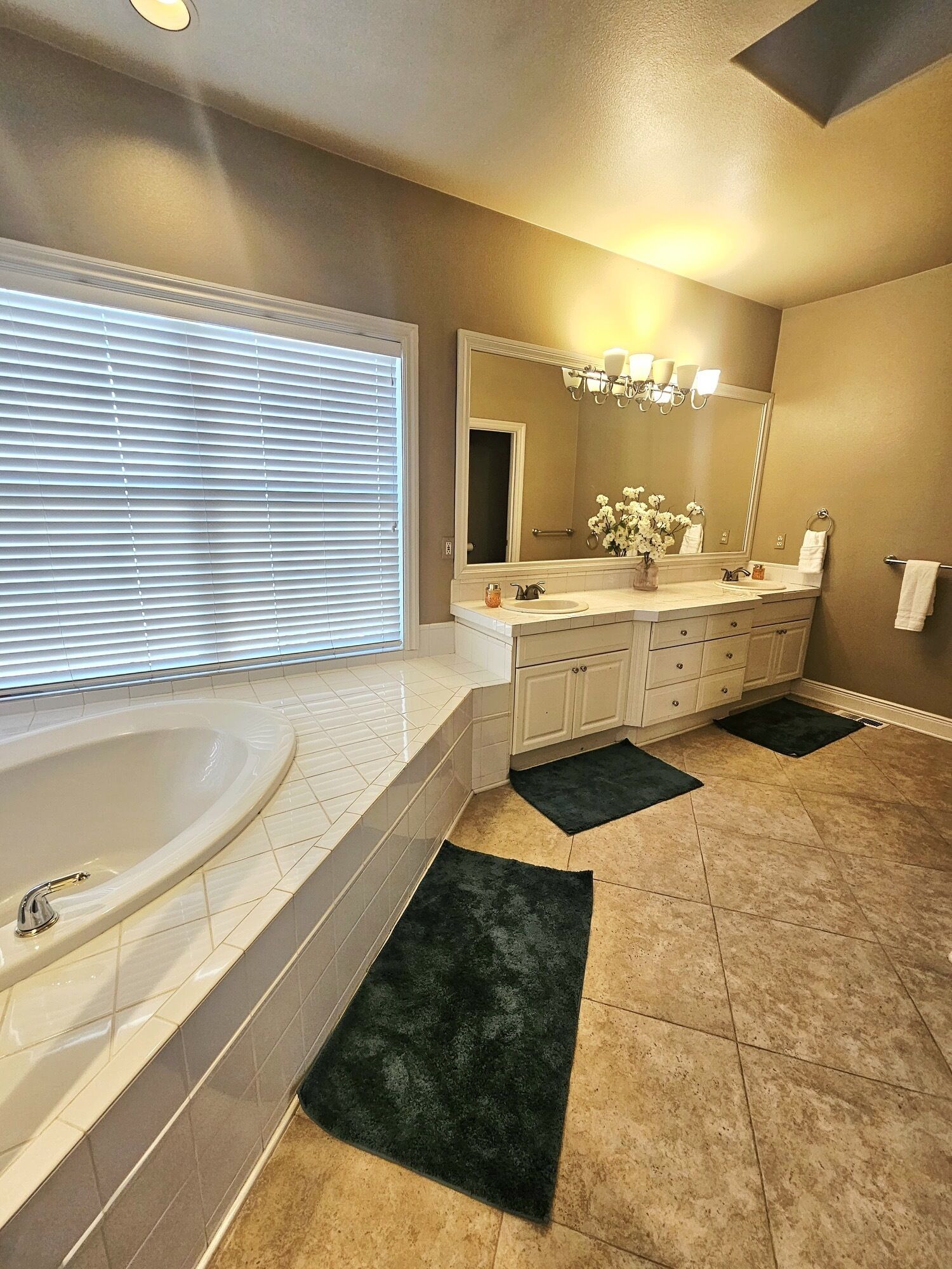 A modern bathroom with a large bathtub, a double sink vanity, and a large mirror.