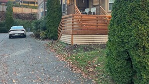 Une maison à deux étages avec une terrasse en bois, un porche à l’avant et un garage.