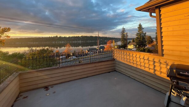 Une maison en bois dotée d’un balcon donnant sur un lac et une zone boisée.