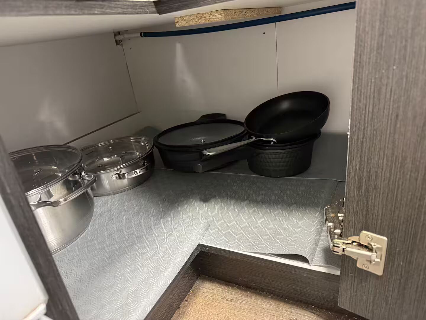 Eine kleine Küche mit Edelstahlarbeitsflächen, einer schwarzen Pfanne und verschiedenen Edelstahltöpfen und -pfannen.