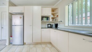 Una cocina equipada con refrigerador, microondas y estufa, con gabinetes y una ventana.
