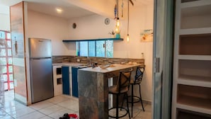 Een moderne keuken met een inbouwkoelkast, een bar met krukken, en een groot raam dat voor natuurlijk licht zorgt.