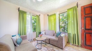 A living room with a sofa, a small round table, and a wooden floor. - Hummingbird jungle (La Fortuna)