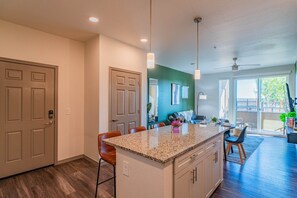 A modern kitchen with a granite countertop, wooden cabinets, and a bar area. - Walk To Stadium with Balcony-Pool-Gym-Parking-W/D (Glendale)