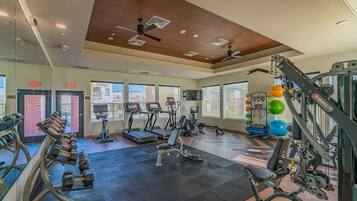 Une salle de sport équipée de tapis de course, d’appareils de musculation et d’un rameur.