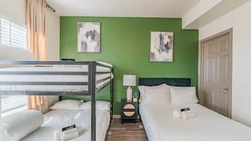 A hotel room with bunk beds, a bedside table with a lamp, and artwork on the walls.