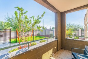Un balcon donnant sur un espace paysager aménagé, avec une rambarde en métal et une chaise.