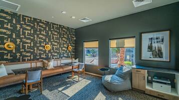 A modern lounge area with a patterned wall, seating arrangements, and large windows.