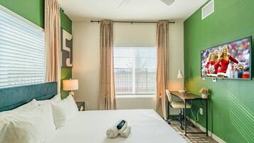 Une chambre d’hôtel avec un lit, un bureau, une télévision et une fenêtre avec des rideaux.