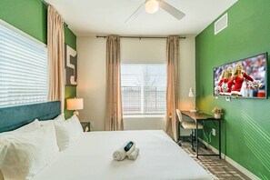 Ein Hotelzimmer mit einem Bett, einem Schreibtisch, einem Fernseher und einem Fenster mit Vorhängen.
