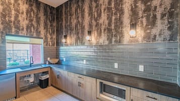 A kitchen with a rustic wall, a built-in microwave, and a window overlooking a balcony.