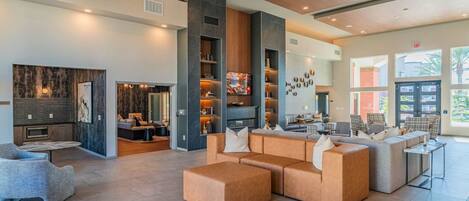 A spacious lobby with a modern design, featuring a large seating area, a fireplace, and a television.