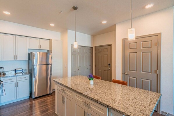 A modern kitchen with stainless steel appliances, granite countertops, and pendant lighting.