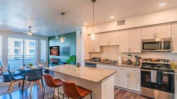 A modern kitchen with a central island, stainless steel appliances, and a dining area with bar stools.