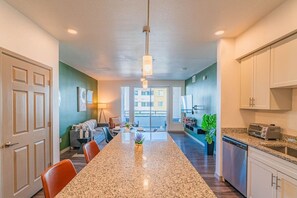 A modern kitchen with granite countertops, a central island, and a dining area with chairs.