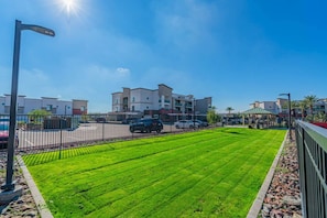 Un jardí ben cuidat amb una tanca, un fanal i edificis moderns al fons.