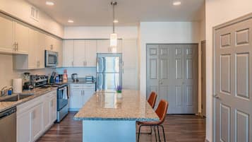 A modern kitchen with a central island, stainless steel appliances, and a bar stool.