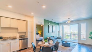 A modern kitchen with white cabinets, a dishwasher, and a dining area with a round table and chairs. - Stadium Area Unit w/ Balcony,Pool,Gym,Parking,W/D (Glendale)
