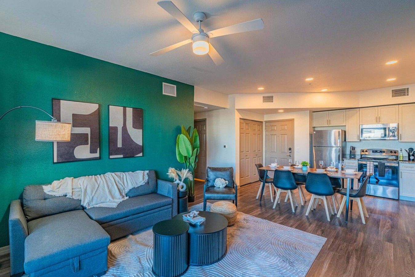 A modern living room with a sofa, coffee table, and a dining area with chairs and a table.