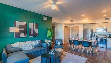 A modern living room with a sofa, coffee table, and a dining area with chairs and a table.