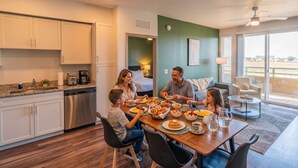 Una familia cenando en una cocina moderna con comedor, un balcón con vistas y un ventilador de techo.