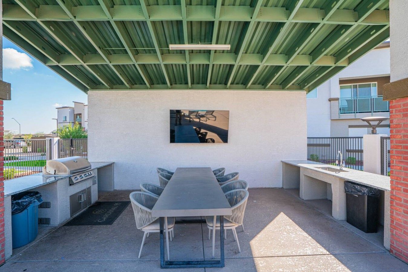Patio esterno con barbecue, tavolo da pranzo e sedie.