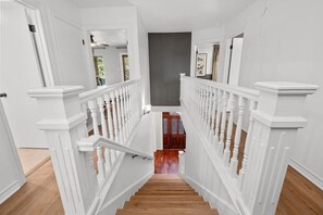 Un escalier avec des balustrades blanches et une main courante en bois menant à un palier.