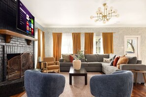 A living room with a fireplace, a sofa set, a coffee table, and a television mounted on the wall. - HeatedPool PickleBall Basktball Golf FirePit Games (San Antonio)