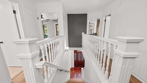 A staircase with white railings and wooden steps leading to a dark-colored landing area. - HeatedPool PickleBall Basktball Golf FirePit Games (San Antonio)