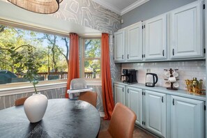 A kitchen with a dining table, chairs, a coffee maker, and cabinets. - HeatedPool PickleBall Basktball Golf FirePit Games (San Antonio)