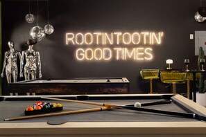 Une table de billard avec un panneau néon sur lequel on peut lire : « AMUSEZ-VOUS À FOND » et un bâton de billard.