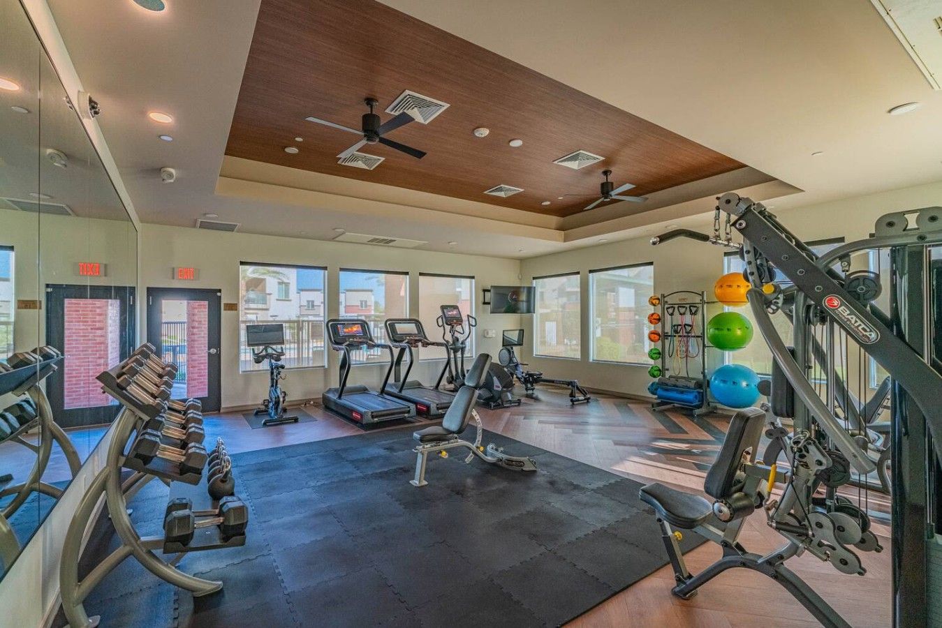 Un gimnasio con cintas de correr, máquinas de pesas y pelotas de ejercicio.