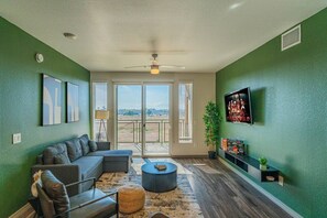 A living room with a sectional sofa, a coffee table, and a TV mounted on the wall. - Spot Near Westagate w/Balcony,Pool,Gym,Parking,W/D (Glendale)