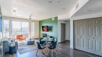 A spacious living area with a dining table, chairs, and a television mounted on the wall.