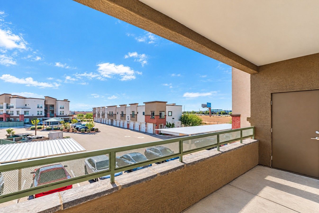 Un balcon donnant sur un parking et des immeubles.