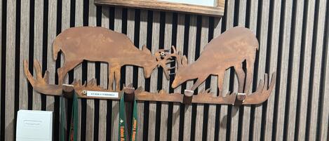 A wooden wall with a welcome sign, two moose antlers, and lanyards with ID badges.