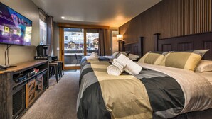 A hotel room with a large bed, a desk with a computer, a TV on the wall, and a view of the outside. - First Tracks at Northstar_Corner Unit In Village, Kitchen, 1GWifi, Darts, Covered Parking +NPOA Pass (Truckee)