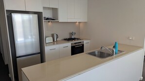 Een kleine keuken met een roestvrijstalen koelkast, een inbouwvaatwasser, een gasfornuis en een gootsteen met een kraan.